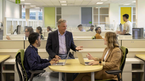 three coworkers chatting at a desk